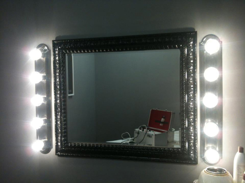 Vertical light fixtures on either side of a bathroom mirror.