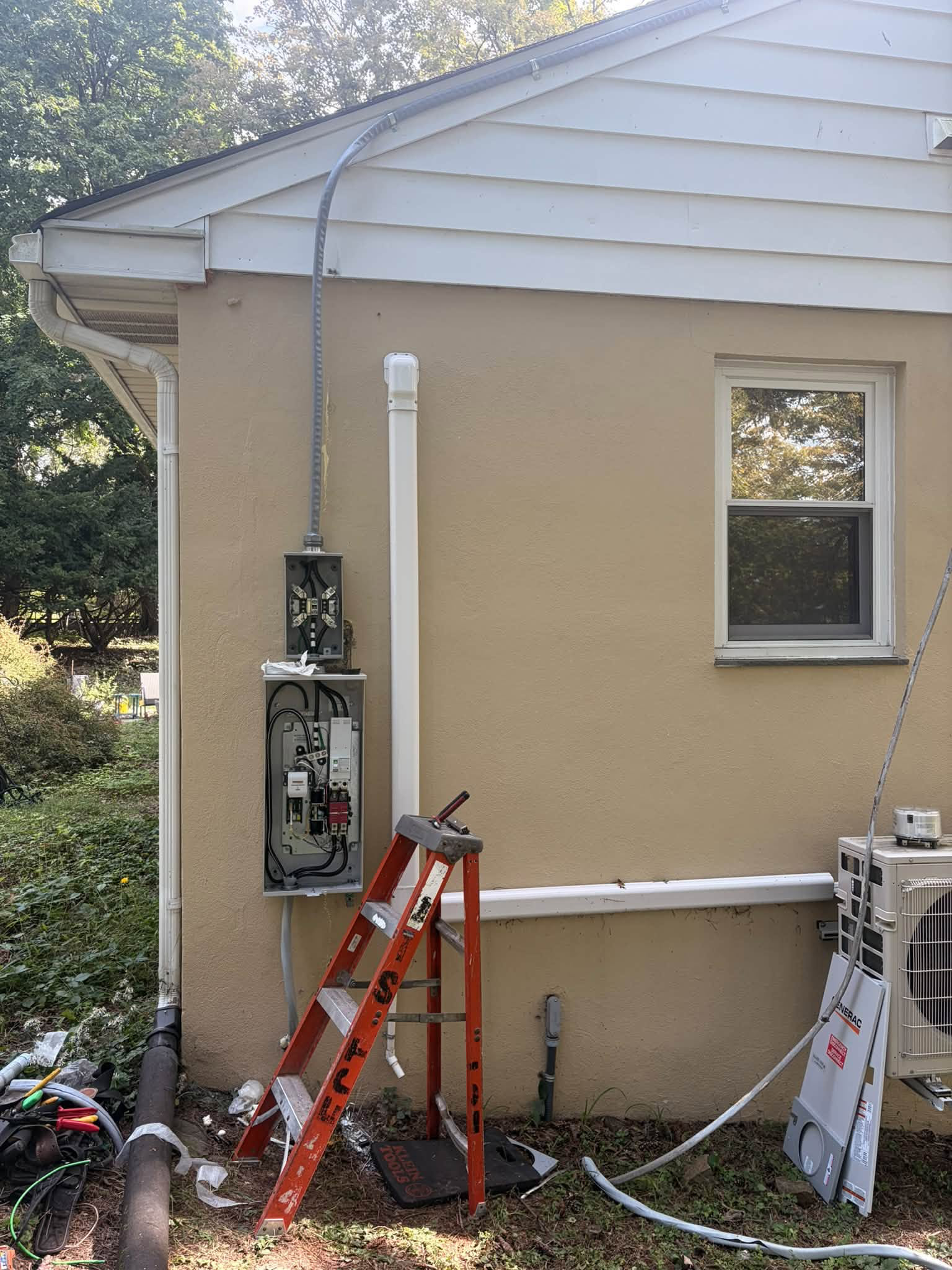 Exterior electrical service and generator transfer equipment during installation, with covers removed. Work in progress.